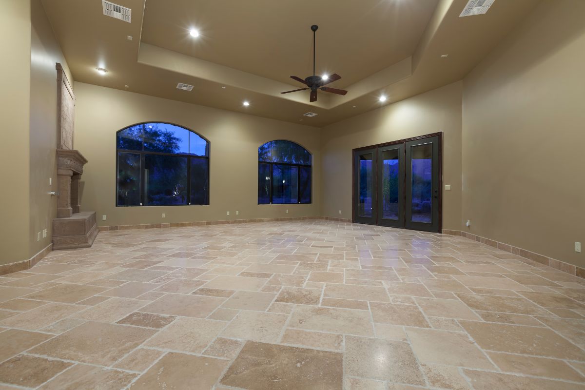 A spacious living room featuring tile flooring and large windows that allow ample natural light to enter the space.
