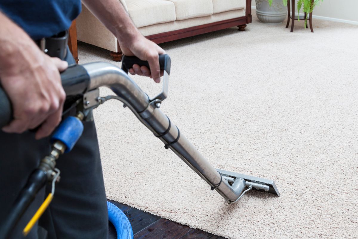 A man using a vacuum cleaner to clean a carpet, demonstrating effective home maintenance and cleanliness. 