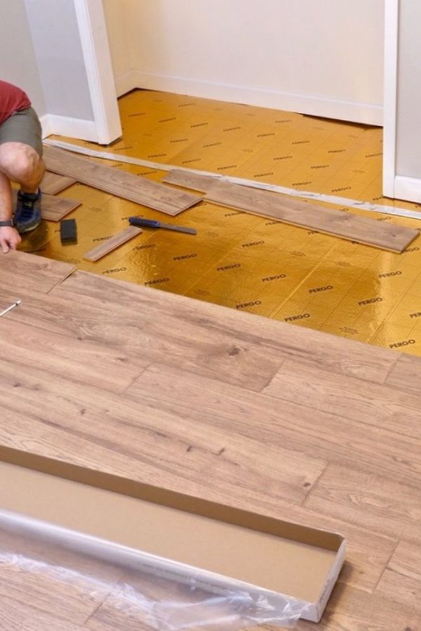 A man works on installing wood flooring in a room, highlighting flooring services in Las Vegas, NV.