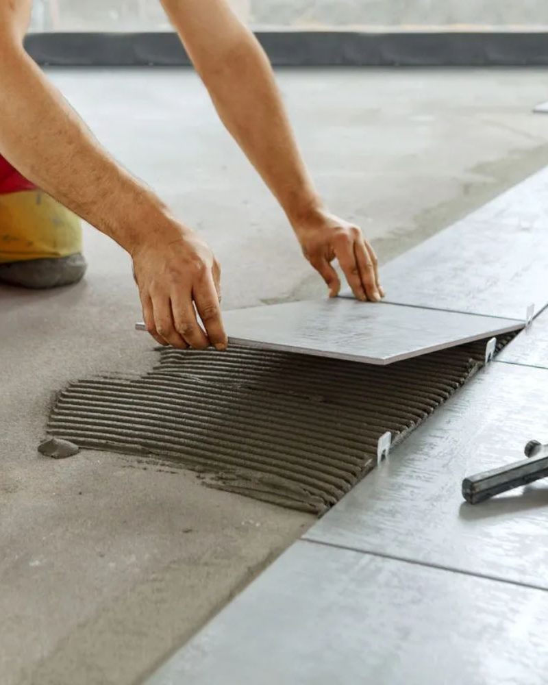 A man engaged in laying tile on the floor, illustrating flooring services in Las Vegas, NV.