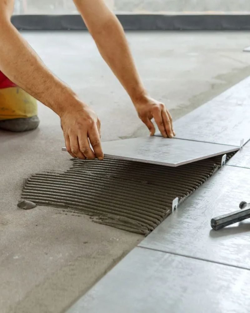 A man engaged in laying tile on the floor, illustrating flooring services in Las Vegas, NV.