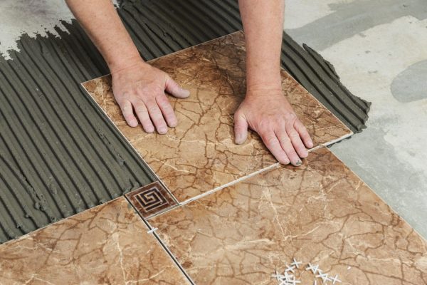 An individual engaged in tile installation on a floor, illustrating tile flooring services in Las Vegas, NV.